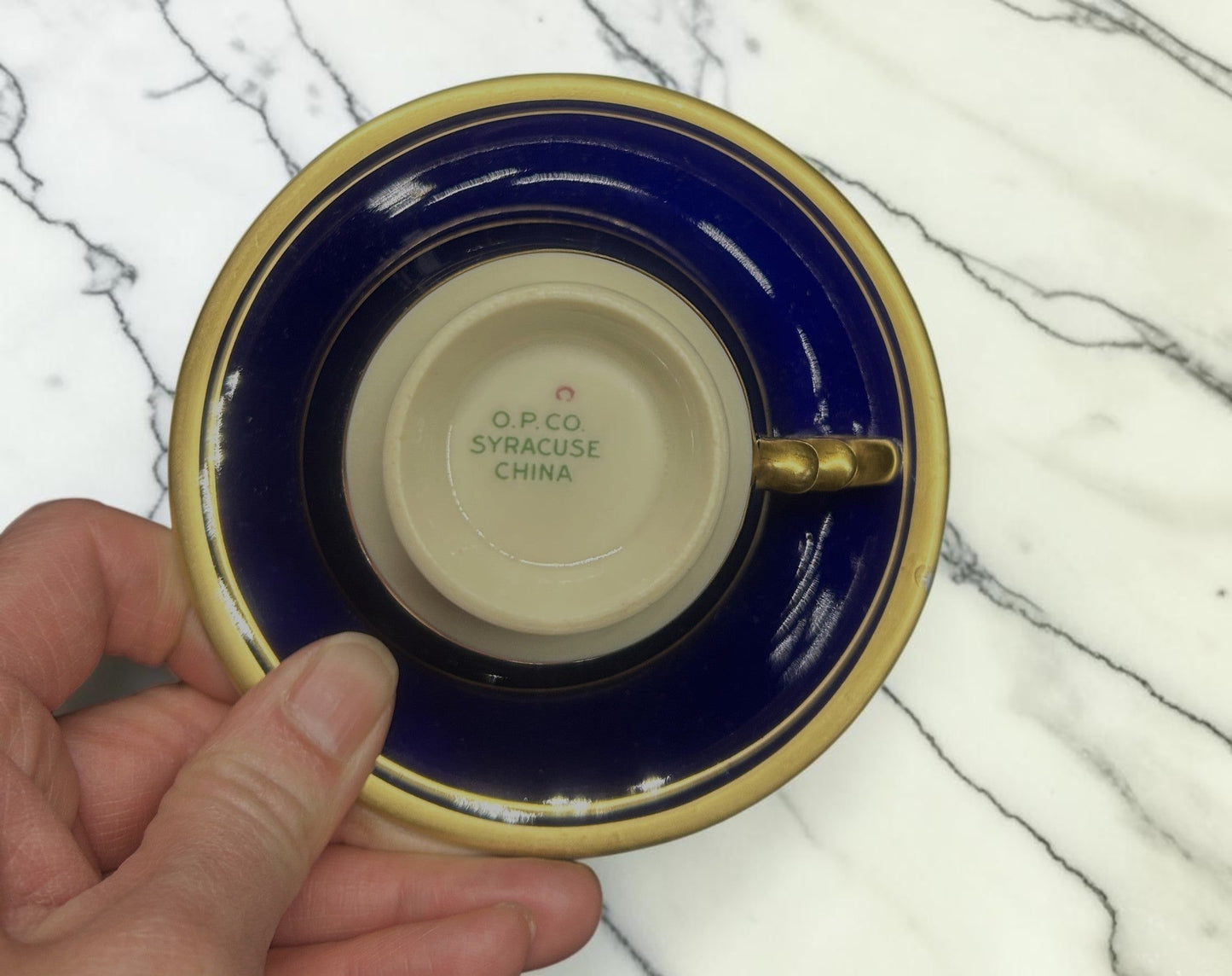 C&C Atelier cobalt blue porcelain tea cup and saucer with gold trim and embossed detailing.