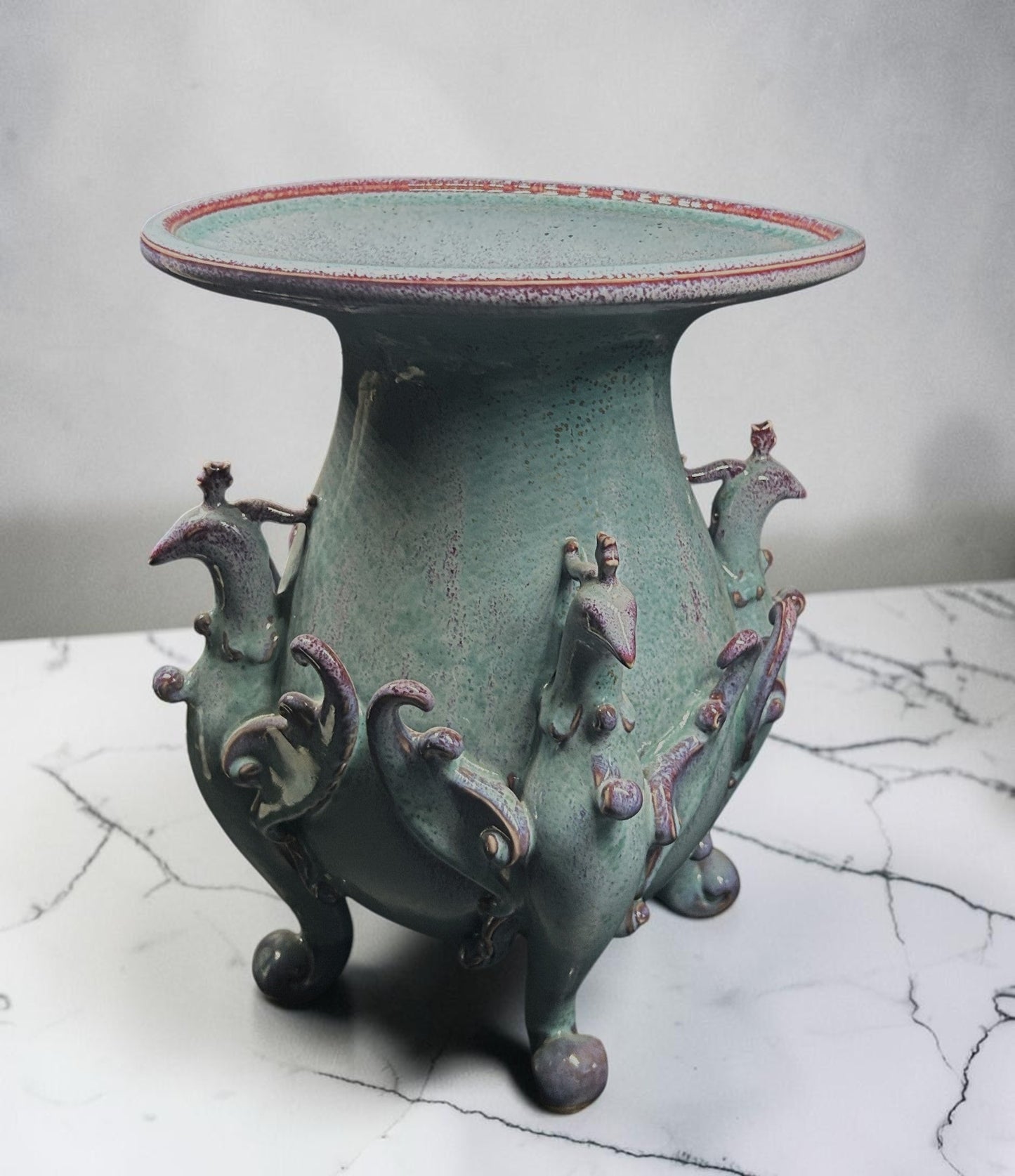C&C Atelier celadon ceramic pedestal vase with purple bird motifs and tripod base.