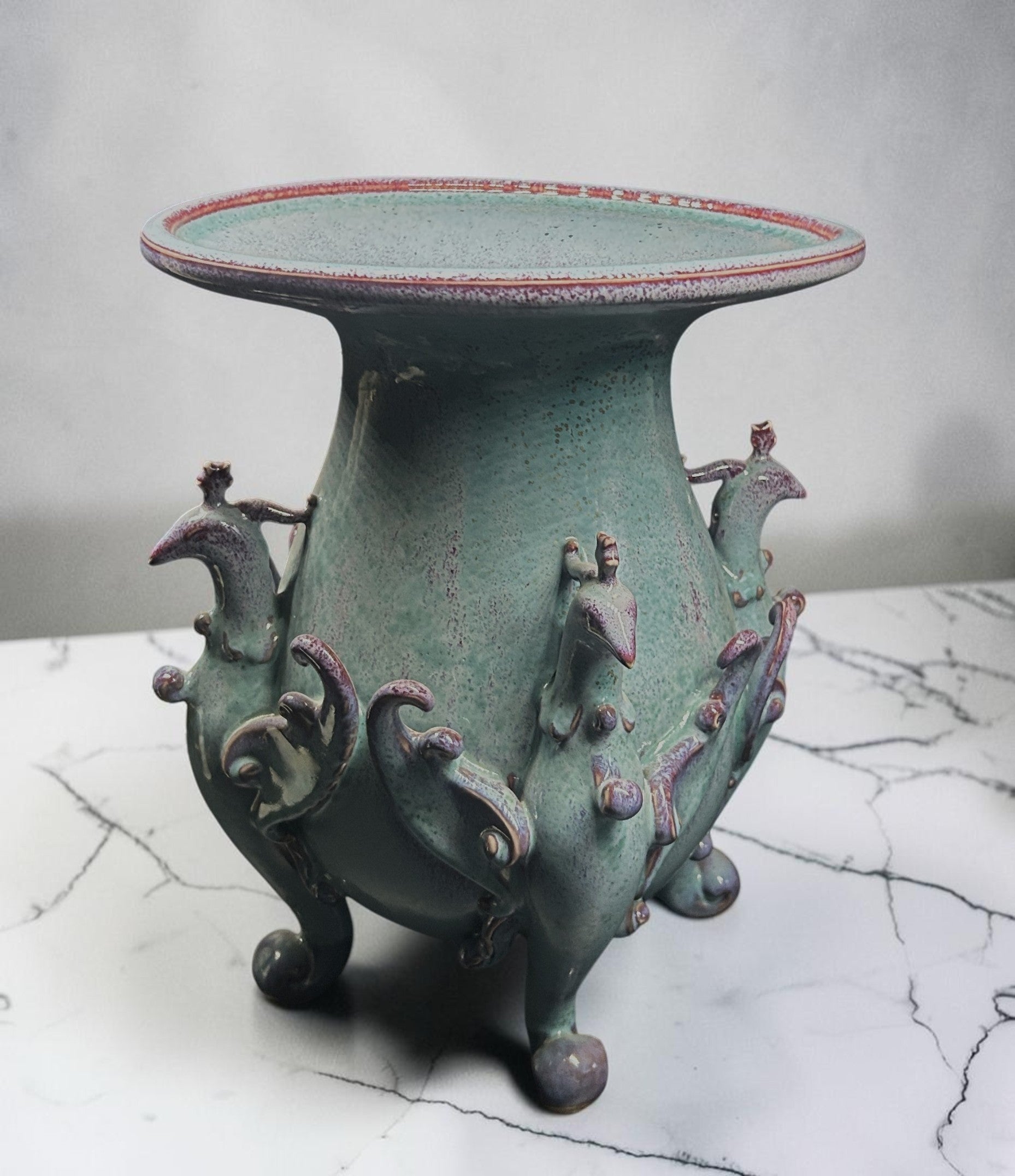 C&C Atelier celadon ceramic pedestal vase with purple bird motifs and tripod base.