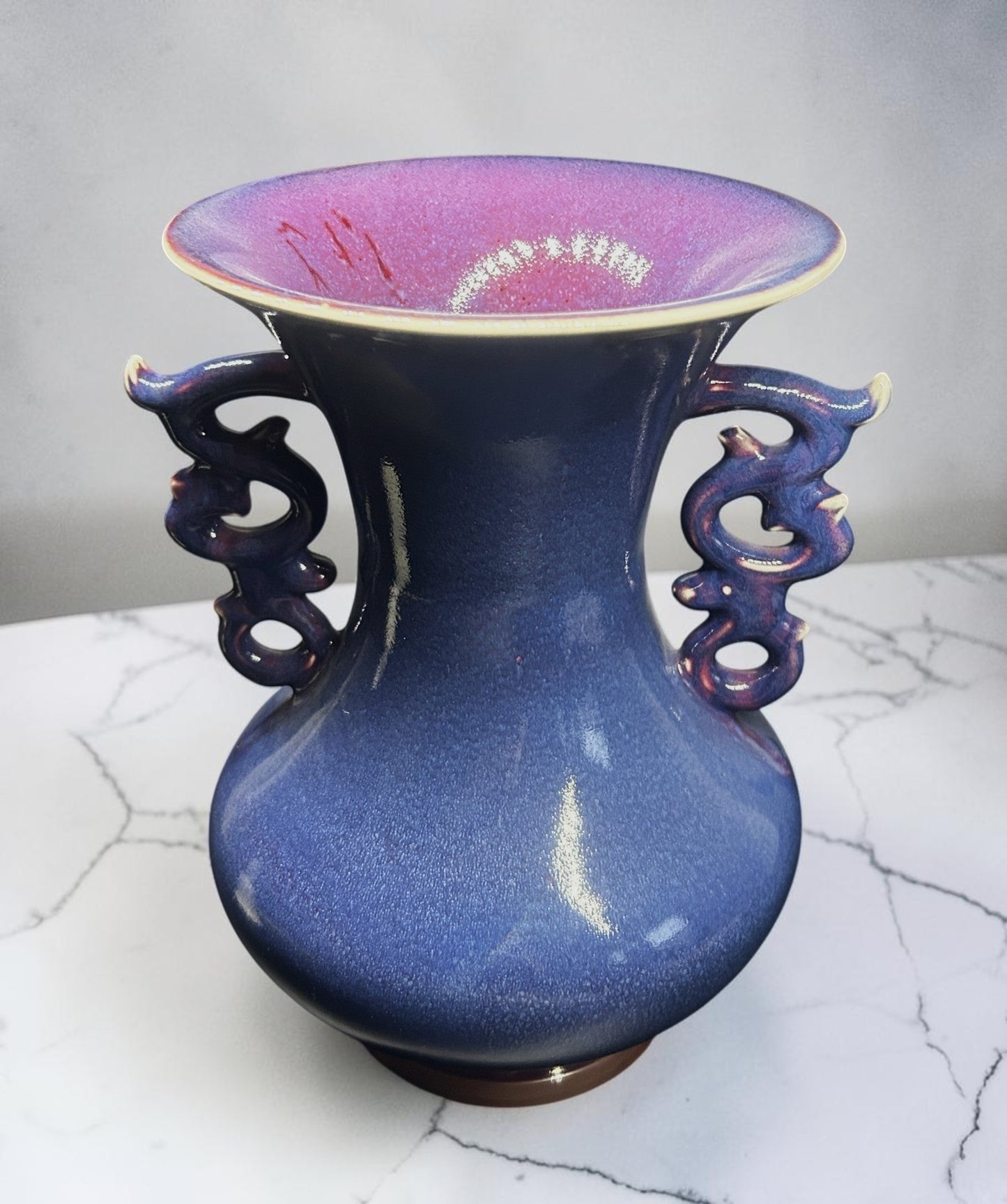 C&C Atelier deep blue ceramic vase with flared rim and dragon-inspired handles, purple interior.