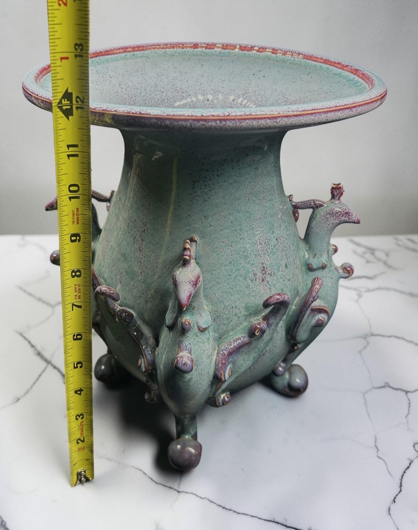C&C Atelier celadon ceramic pedestal vase with purple accents and sculpted bird motifs on a tripod base.