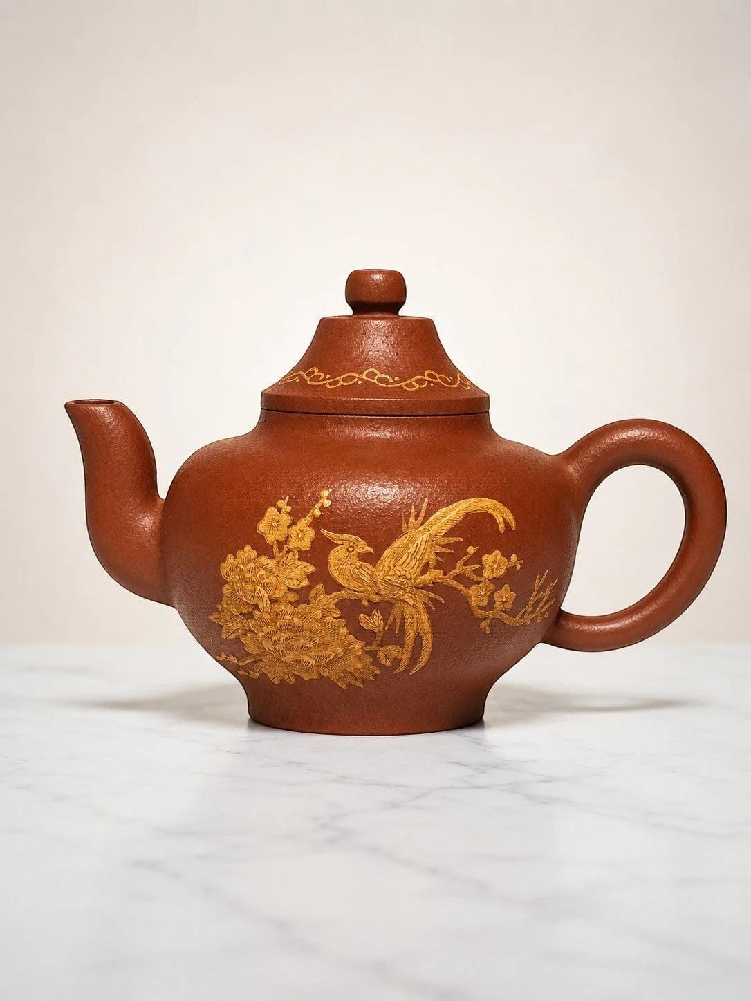 C&C Atelier 凤凰牡丹纹紫砂茶壶，采用优质紫砂泥手工制成，色泽古朴典雅，饰有精美的凤凰与牡丹图案。