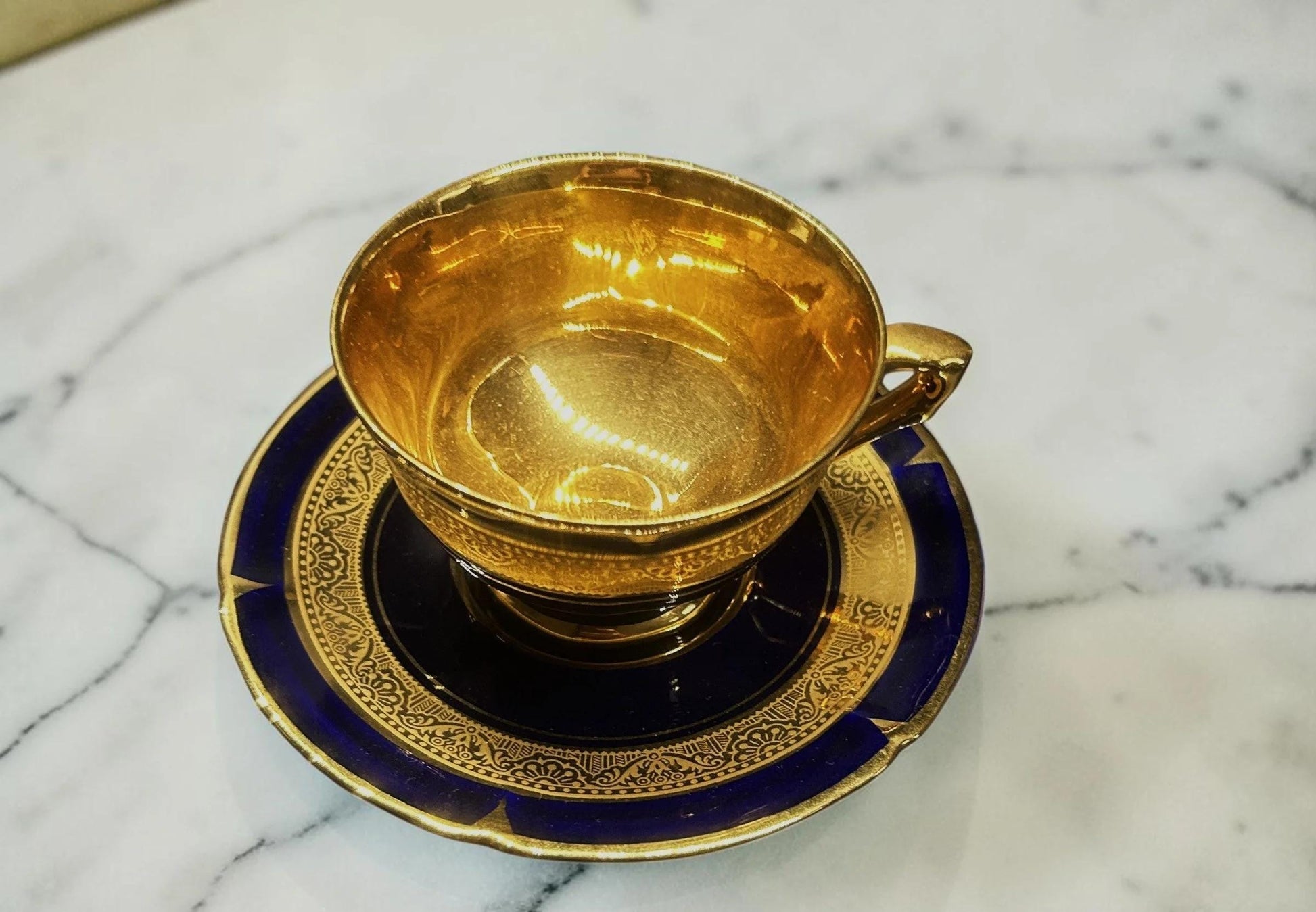 C&C Atelier gilded porcelain teacup and saucer set with cobalt blue exterior and gold detailing.