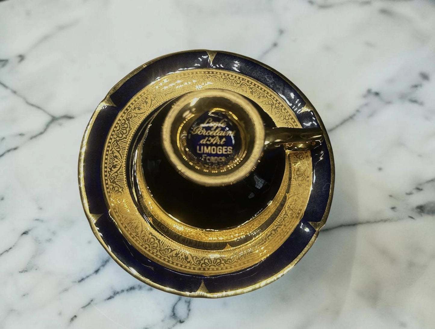 C&C Atelier Gilded porcelain teacup and saucer set with cobalt blue exterior and intricate gold detailing.