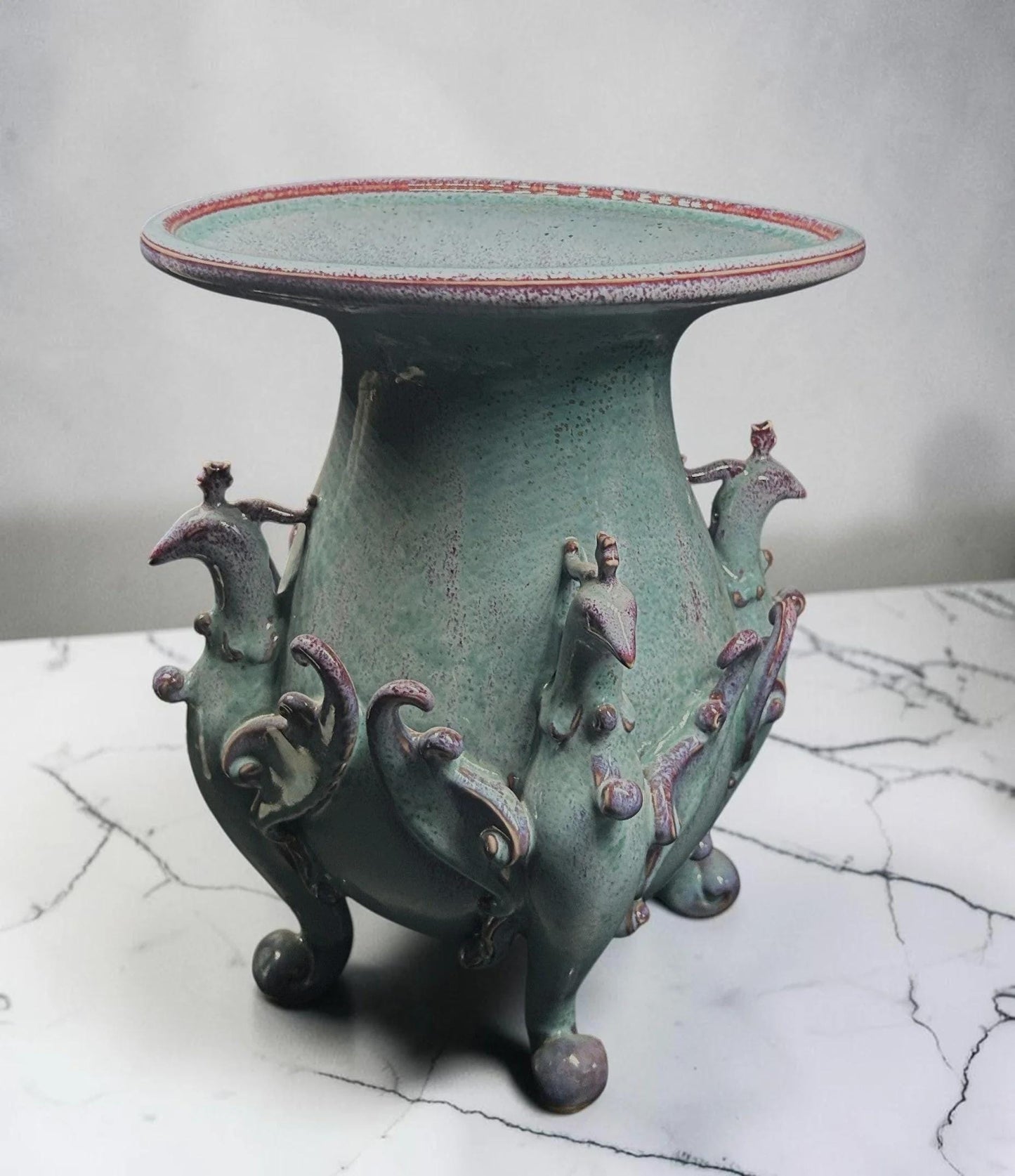 C&C Atelier celadon ceramic pedestal vase with purple bird motifs and tripod base.